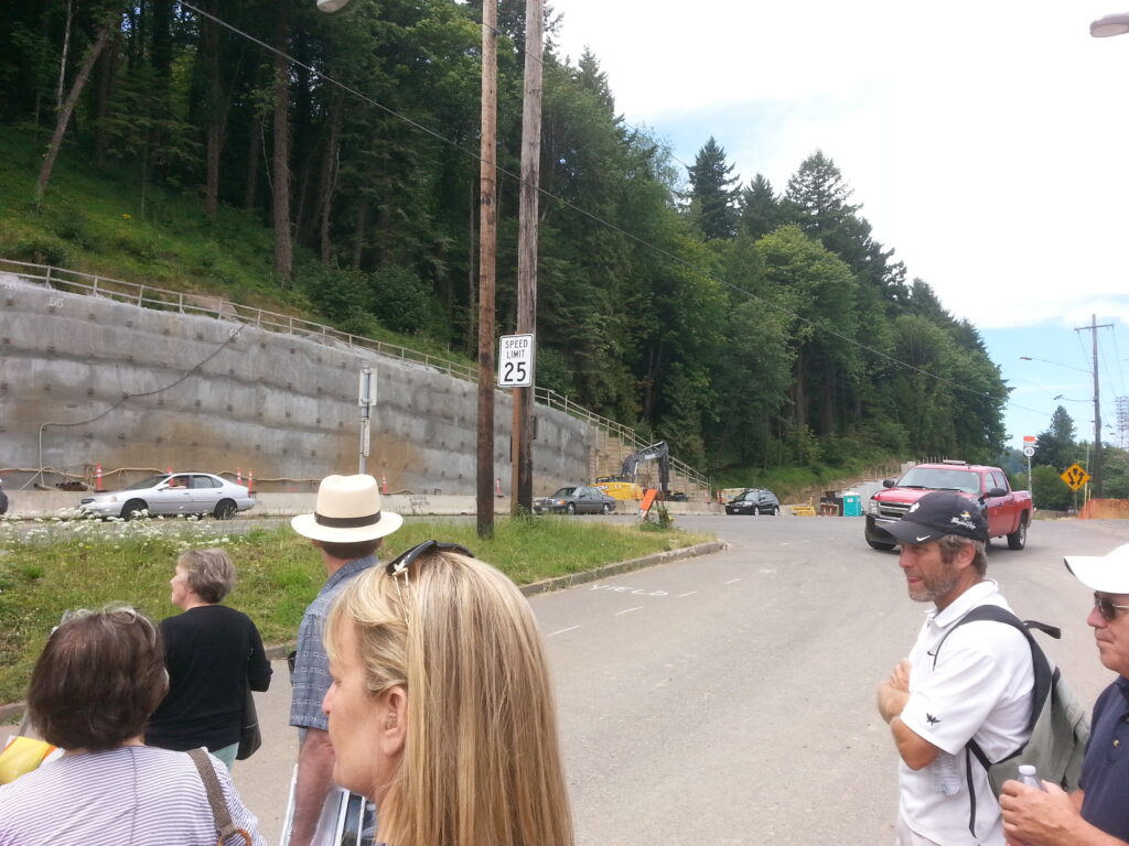 The west side wall construction continues.  This section of wall still has the exposed ends of soil nails visible.  The soil nails extend 60’ into the hillside to stabilize the soil and attach the wall.  Eventually, this wall surface will be covered with the same vertically-striated concrete visible on the most northern end of the hillside.