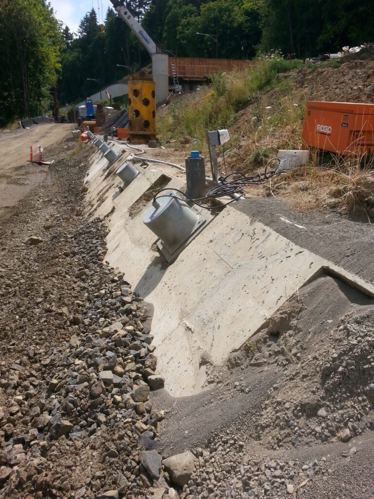 One of the main reasons the Sellwood Bridge was damaged in the first place was that the original engineers didn’t realize the west bank of the river was basically a slow-motion landslide.  The pressure over the decades moved the west end and buckled the support structure, so the new bridge will have motion monitoring equipment integrated into its design.  These cylinders are access points to probes that extend deep into the ground.  When the bridge is finished they’ll provide ongoing data on ground movement.  Right now, they’re being used to confirm that all the engineering on the west side to stop the landslide has actually been effective.